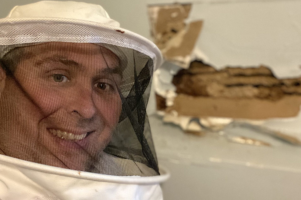 Man in beekeeping suit smiling indoors